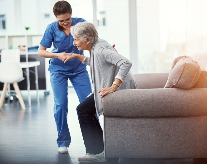 Nurse helping her senior patient up from a chair in Bossier City short-term rehab facility
