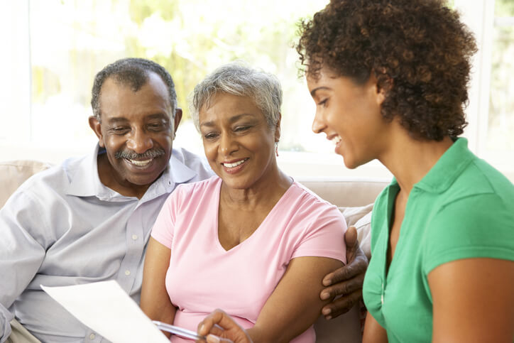 A nurse and a couple sit on a couch reviewing a financial document on Skilled Nursing Care in Bossier City, LA